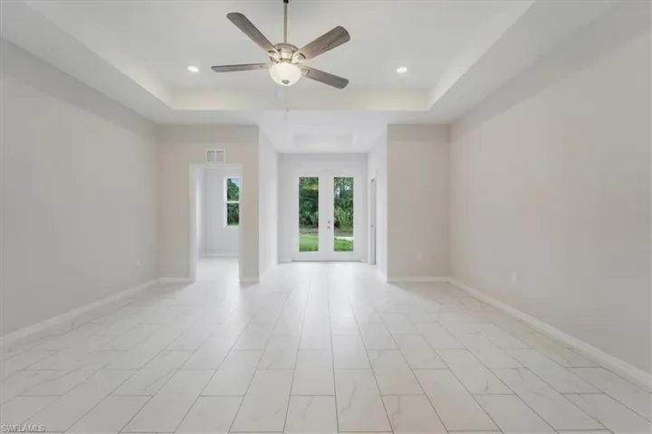 Unfurnished room with a raised ceiling, ceiling fan, french doors, and recessed lighting