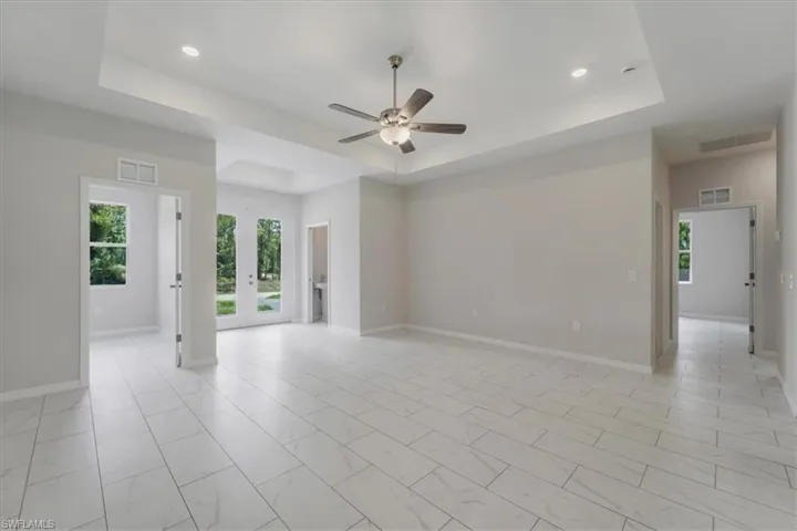 Spare room with ceiling fan, healthy amount of natural light, a raised ceiling, french doors, and recessed lighting