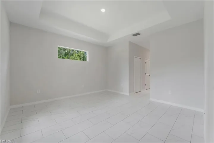 Unfurnished room featuring a tray ceiling and baseboards