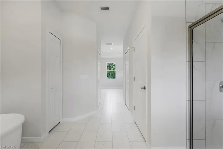 Hallway featuring baseboards and light marble finish floors