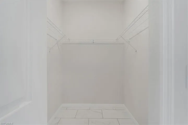 Walk in closet with light marble finish floors