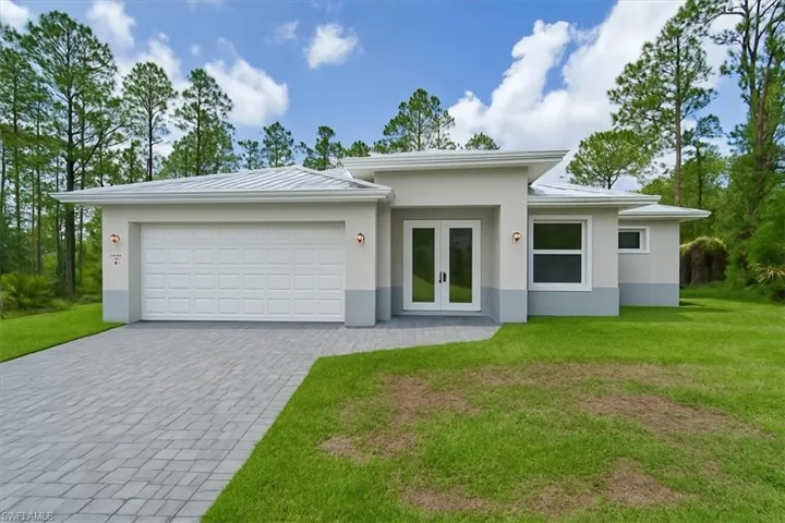 View of front of property featuring french doors, a front yard, an attached garage, decorative driveway, and stucco siding