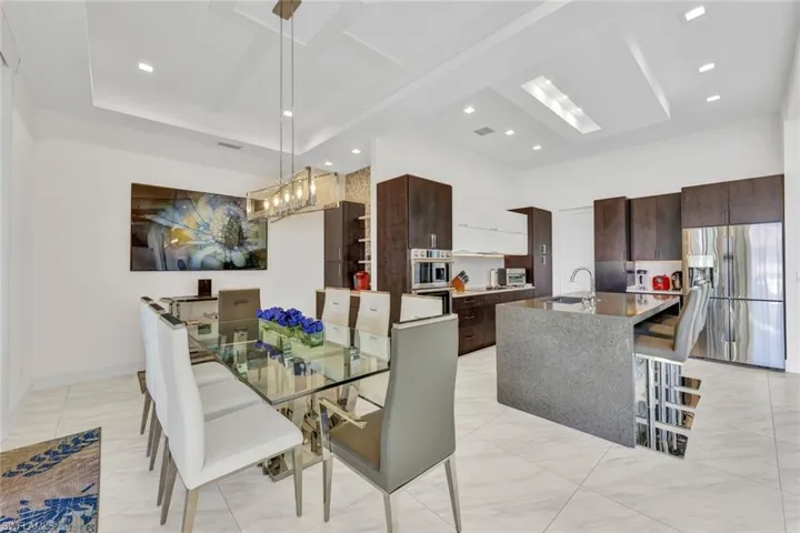 Dining area has a coffee bar with additional sink & concealed coffee maker cabinet complete with tiled accent wall & floating shelves