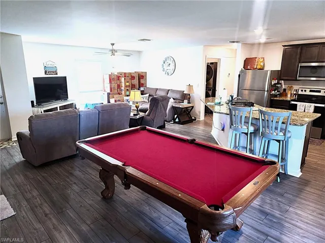 Rec room with ceiling fan, dark hardwood / wood-style flooring, stacked washer / drying machine, and pool table