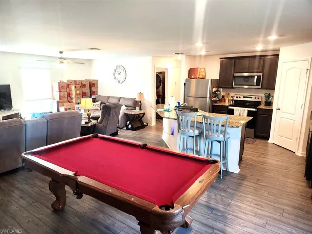 Rec room with stacked washing maching and dryer, ceiling fan, dark wood-type flooring, and billiards