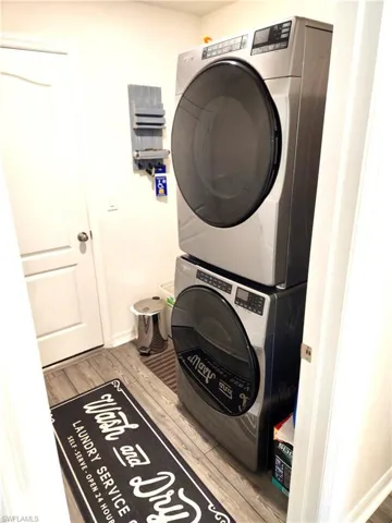 Washroom featuring light wood-type flooring and stacked washer / dryer