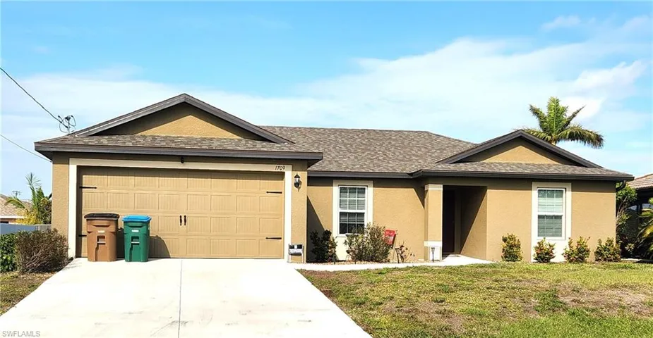 Ranch-style home featuring a front yard and a garage