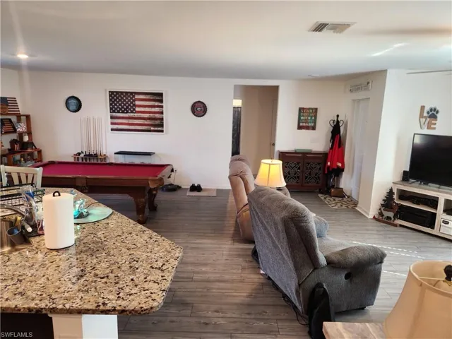 Living room with wood-type flooring and billiards