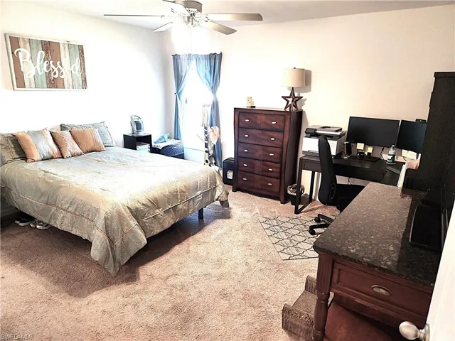Carpeted bedroom featuring ceiling fan
