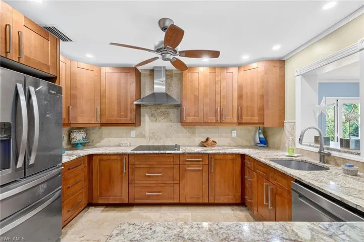 Kitchen with appliances with stainless steel finishes, light stone countertops, brown cabinets, and recessed lighting