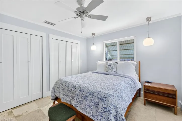 Bedroom with two closets, crown molding, and a ceiling fan