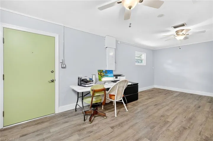 Office space with light wood-type flooring, a ceiling fan, and crown molding