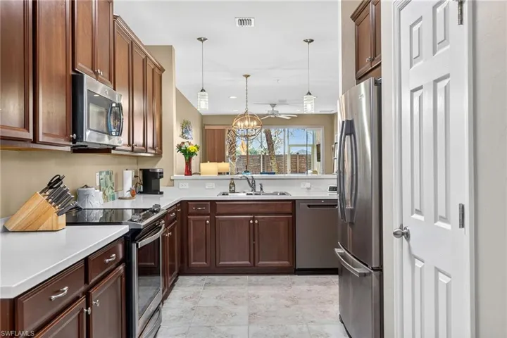 Kitchen featuring appliances with stainless steel finishes, pendant lighting, a chandelier, and light tile patterned floors