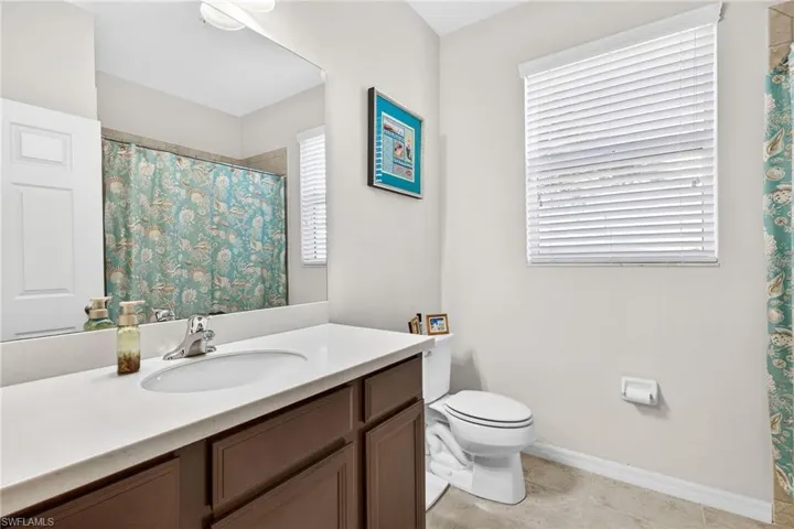 Bathroom featuring a shower with curtain, vanity, and light tile patterned floors