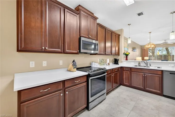 Kitchen featuring appliances with stainless steel finishes, a chandelier, hanging light fixtures, a peninsula, and ceiling fan