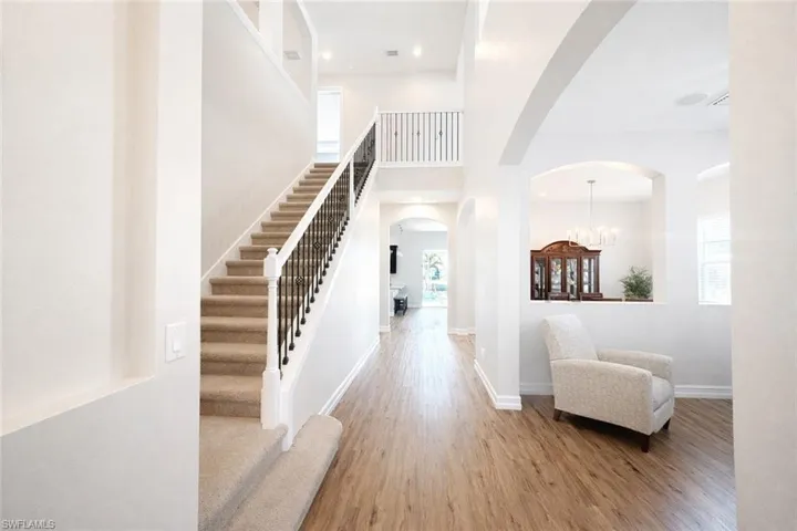 Foyer featuring arched walkways, wood finished floors, a high ceiling, and hanging lights