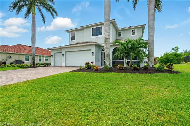 Traditional-style home featuring stucco siding, decorative driveway, a garage, central AC, and a front lawn