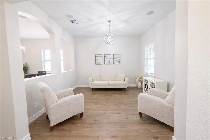 Living area featuring wood finished floors, arched walkways, and suspended lighting
