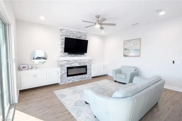 Living room featuring a ceiling fan, light wood-style floors, and a fireplace