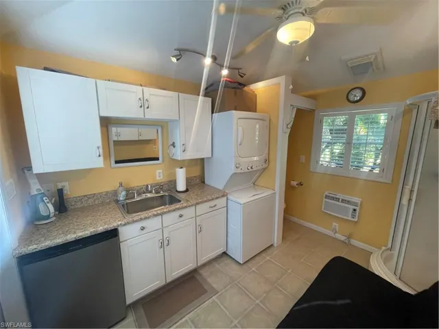 Kitchen with white cabinets, dishwasher, stacked washer / drying machine, ceiling fan, and light countertops