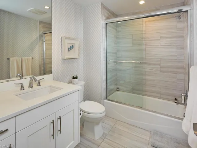 Full bathroom with combined bath / shower with glass door, vanity, and toilet