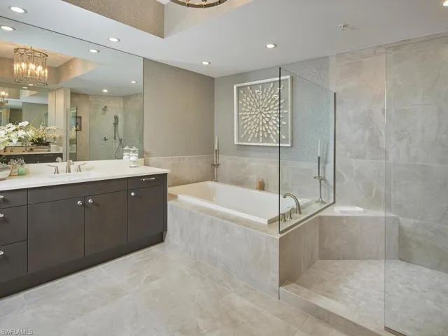 Bathroom featuring a notable chandelier, vanity, and separate shower and tub