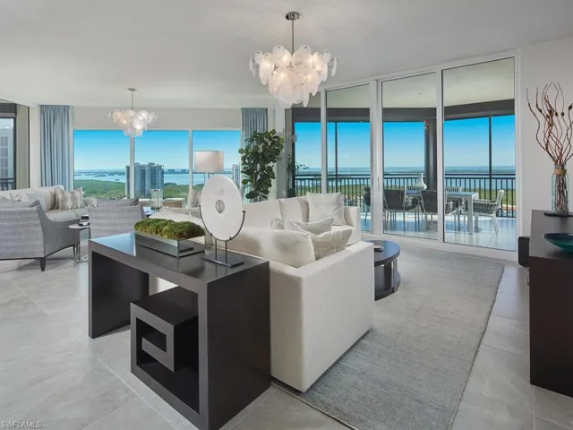 Living room with a notable chandelier, floor to ceiling windows, and a water view