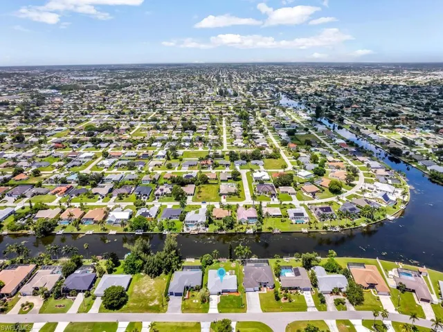 Aerial view of property and surrounding area featuring a nearby body of water and nearby suburban area