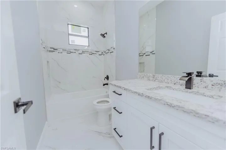 Full bathroom featuring tiled shower / bath, vanity, and toilet