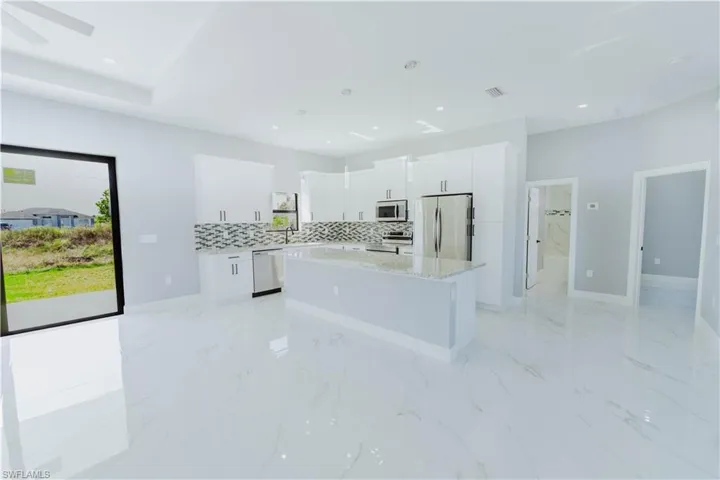 Kitchen with white cabinetry, hanging light fixtures, a kitchen island, and appliances with stainless steel finishes