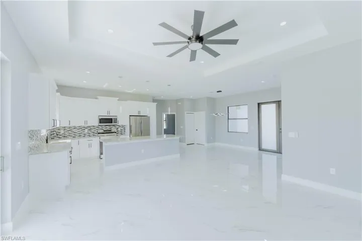 Kitchen featuring tasteful backsplash, appliances with stainless steel finishes, a raised ceiling, a kitchen island, and white cabinets