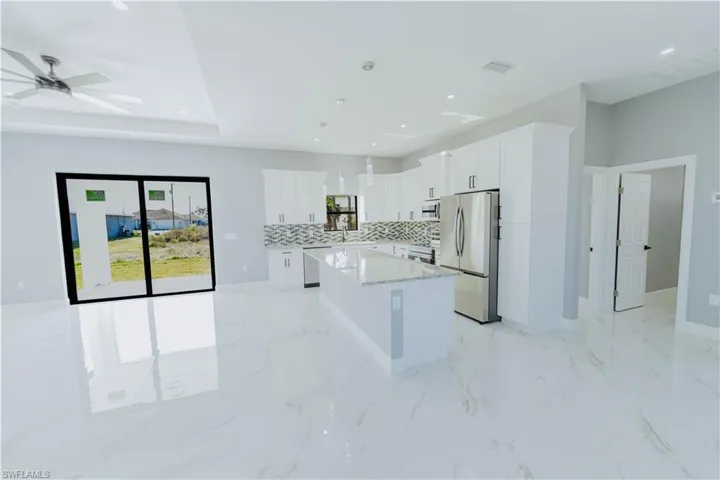 Kitchen with white cabinetry, a kitchen island, pendant lighting, and stainless steel refrigerator