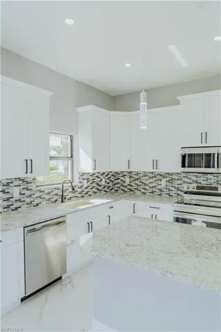 Kitchen with sink, decorative light fixtures, stainless steel appliances, and white cabinets