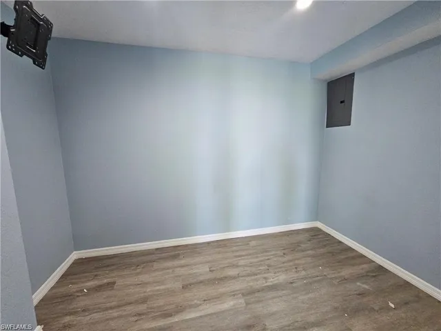 Unfurnished room featuring electric panel and hardwood / wood-style floors