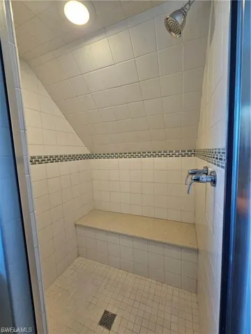 Bathroom featuring tiled shower and lofted ceiling