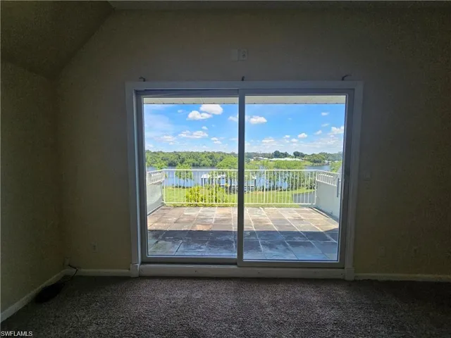 Doorway with lofted ceiling, carpet, a water view, and a healthy amount of sunlight