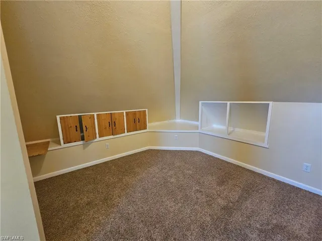 Empty room with lofted ceiling, a textured ceiling, and carpet floors