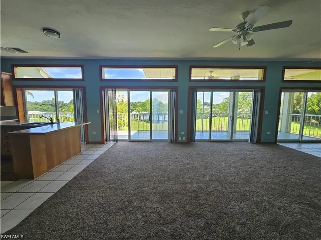 Unfurnished living room with ceiling fan, light tile patterned flooring, a healthy amount of sunlight, and a textured ceiling