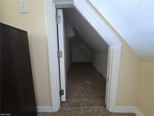 Bonus room featuring vaulted ceiling and dark carpet