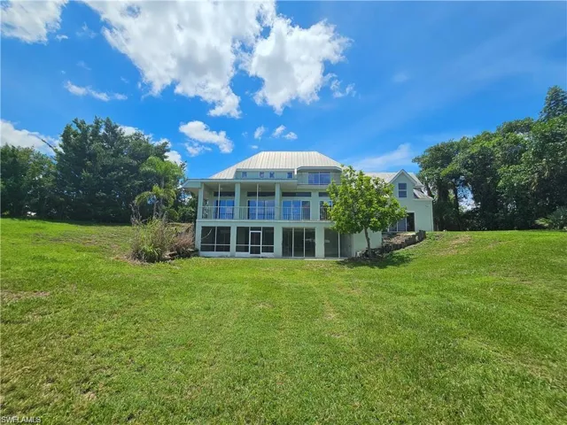 Back of house with a lawn and a balcony