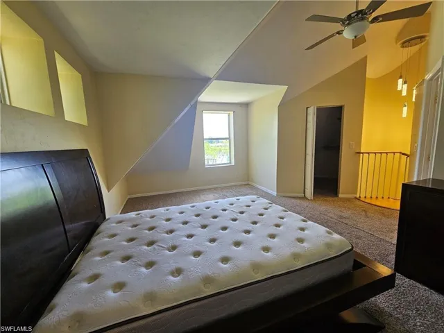 Bedroom with ceiling fan, lofted ceiling, carpet flooring, a walk in closet, and a closet