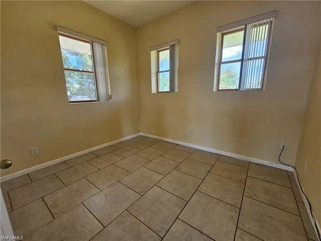 Tiled spare room featuring a healthy amount of sunlight