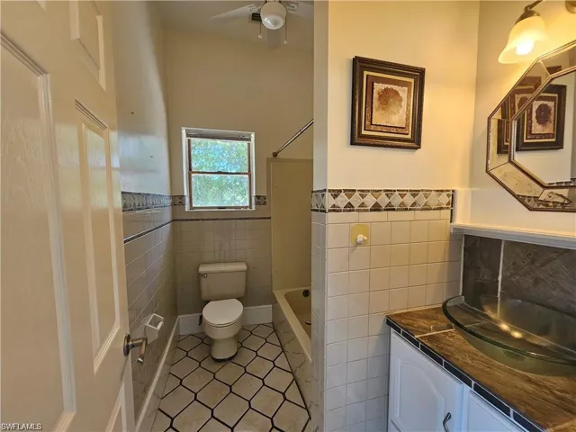 Full bathroom featuring tile walls, tile patterned flooring, vanity, and toilet