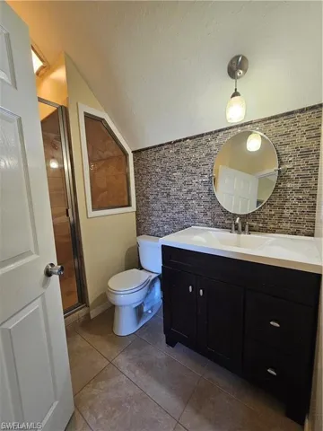 Bathroom with vanity, an enclosed shower, a textured ceiling, tile patterned floors, and toilet