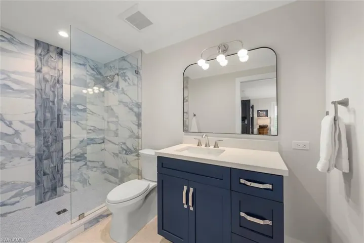 Walk-in shower with tile surround and glass enclosure.