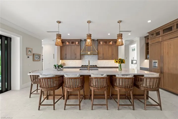 Kitchen featuring warm wood cabinetry and pendant lighting with oversized island and ample bar seating.