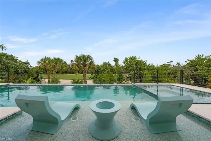 Poolside seating area with built-in table and submerged lounge chairs.