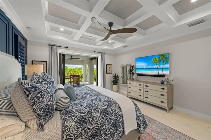 Primary bedroom showcasing sophisticated ceiling design, ceiling fan, and sliding doors for easy access to the patio for relaxation.