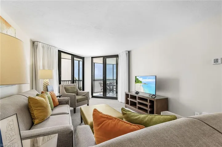Light-toned wall finishes, carpet flooring, and expansive glass doors leading to a balcony
