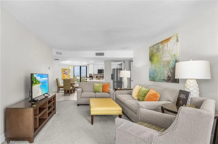 Open-concept living space featuring light-colored walls and carpet flooring